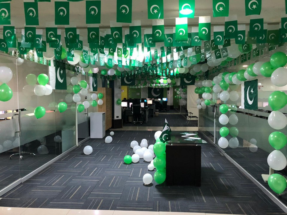 14 August office decoration in Lahore with ceiling flag garlands, green and white balloon arrangements, and patriotic setup for corporate Independence Day celebration.
