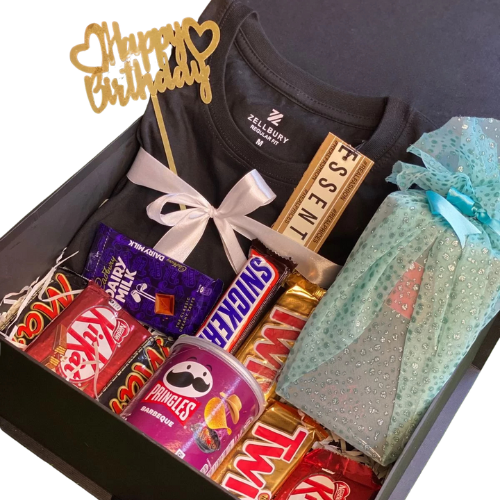 Birthday gift hamper for him with Zellbury black t-shirt, chocolates (Dairy Milk, Snickers, KitKat, Mars, Twix), Pringles chips, wrapped gift, perfume, and Happy Birthday topper.