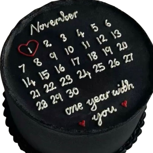 Black cream birthday cake with calendar design, red heart marking a date, and “one year with you” written in white icing.