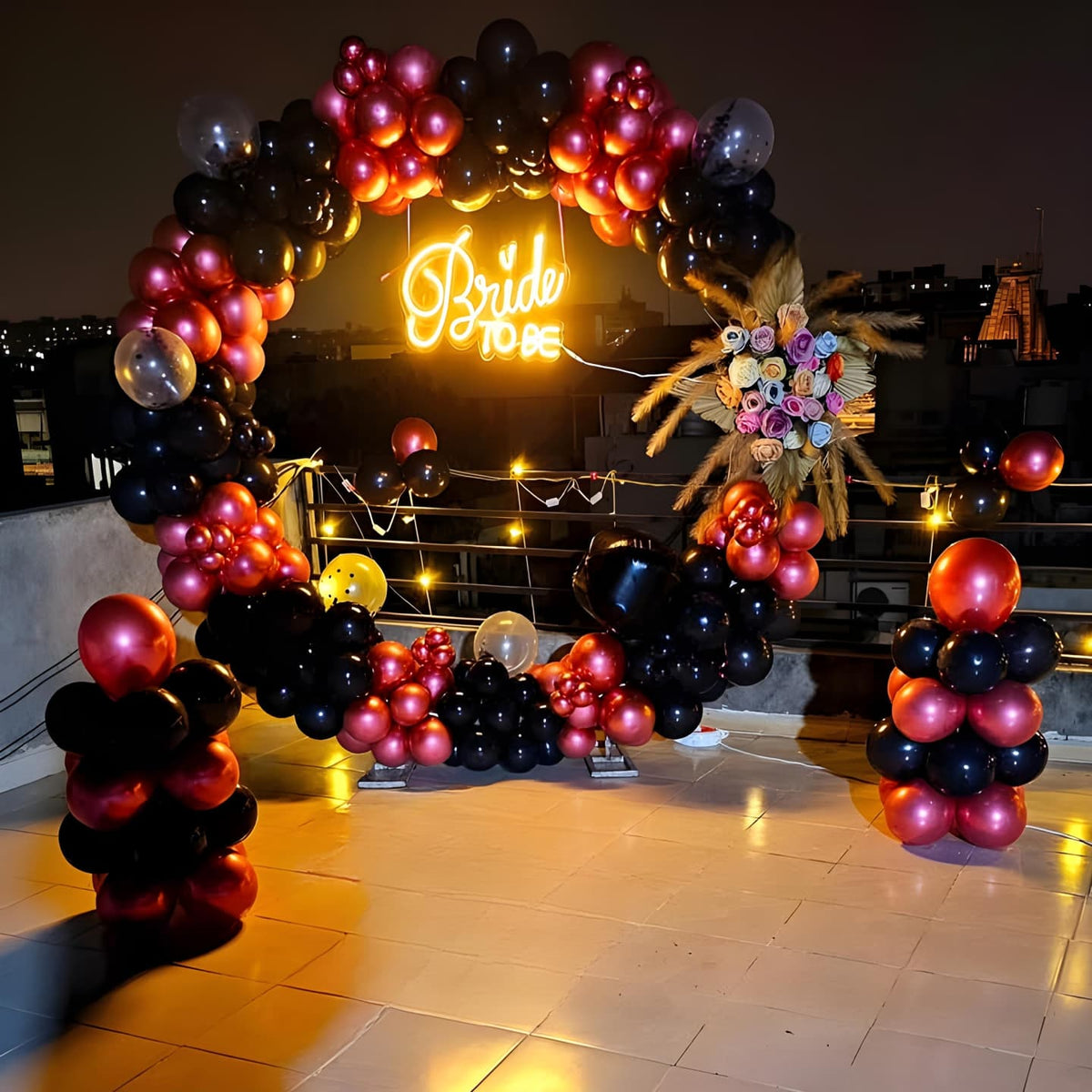Balloon arch with black and pink balloons and a 'Bride-To-Be' neon sign.