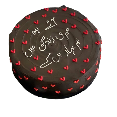 Chocolate anniversary cake decorated with red fondant hearts and Urdu message written in white icing.