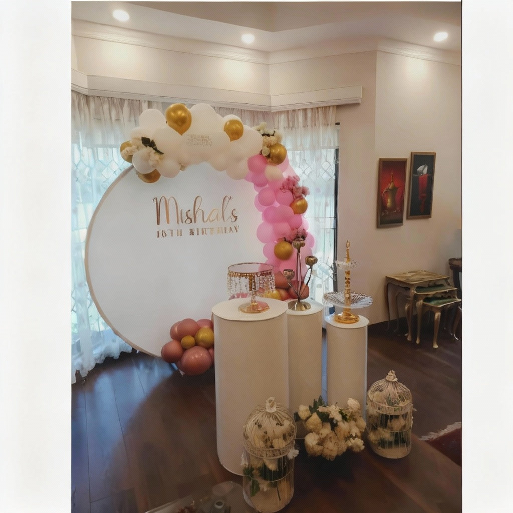 Decorated setup for an 18th birthday celebration with a circular backdrop, balloon arrangement, and decorative pedestals.