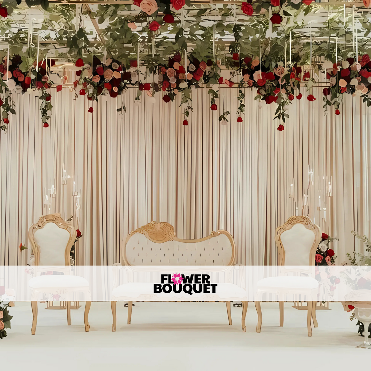 Elegant Barat stage setup with beige drapes, a floral ceiling of red and blush roses, lush green foliage, and white and gold intricately carved chairs and sofa