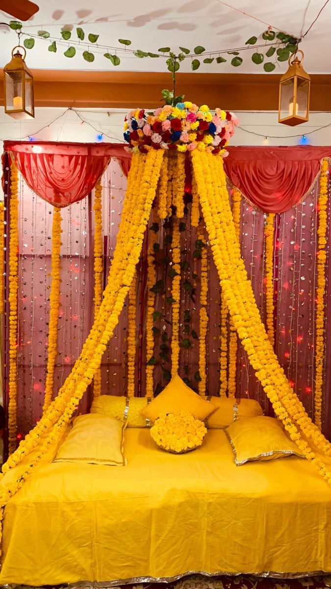 A vibrant Mayo setup featuring yellow marigold flower drapes, soft yellow bedding with decorative pillows, and string lights, creating a joyful and festive ambiance for a pre-wedding ceremony.