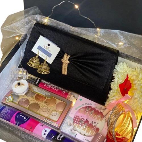 Fashion and beauty gift box with crossbody handbag, eyeshadow palette, ring, jhumkay earrings, bangles, artificial nails, J. body spray, lip gloss, nail paint, KitKat chocolates, and gajray.