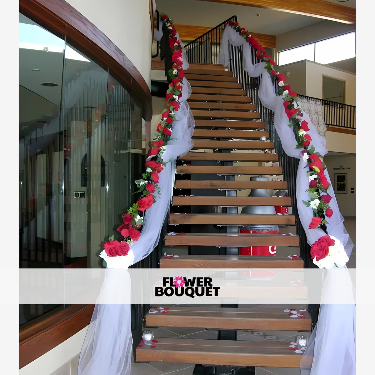 Grand staircase decorated with a floral garland of red and white roses, lush greenery, and elegant sheer white fabric draping, perfect for weddings and upscale events