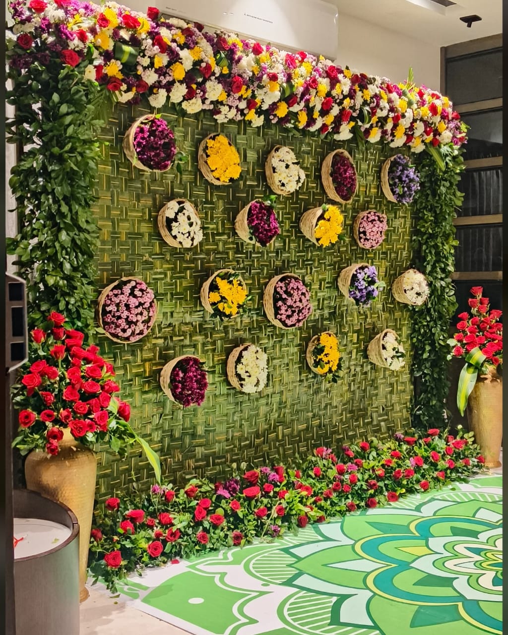 Green wall backdrop with basket flowers and vibrant greenery.