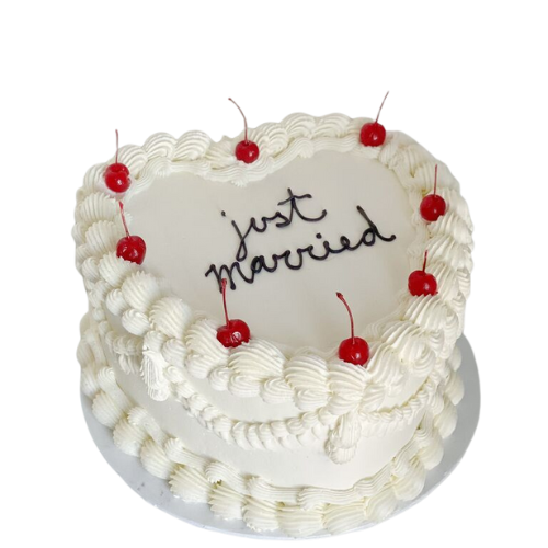 Heart-shaped white wedding cake with cherries and “Just Married” message