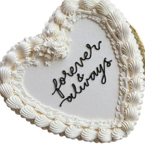 Heart-shaped white wedding cake with “Forever & Always” message in black icing