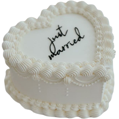 Heart-shaped white wedding cake with “Just Married” message in black icing
