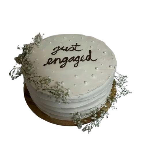 Just Engaged cake with white icing, pearl decorations, and floral accents.