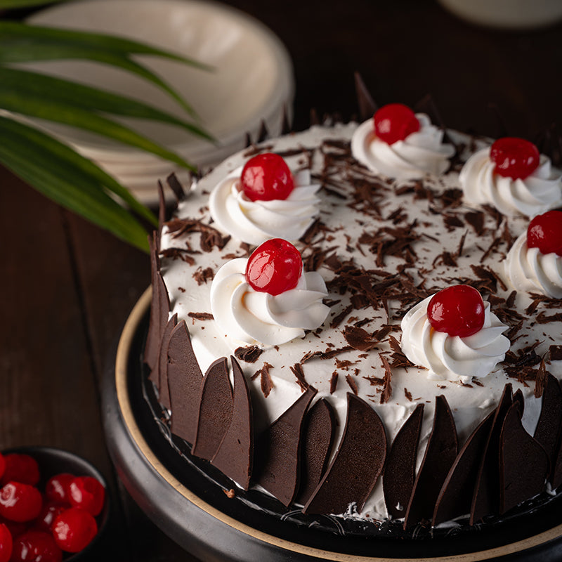 "Kitchen Cuisine Black Forest Cake with whipped cream, cherries, and chocolate shavings, available in Lahore, Karachi, and Islamabad"