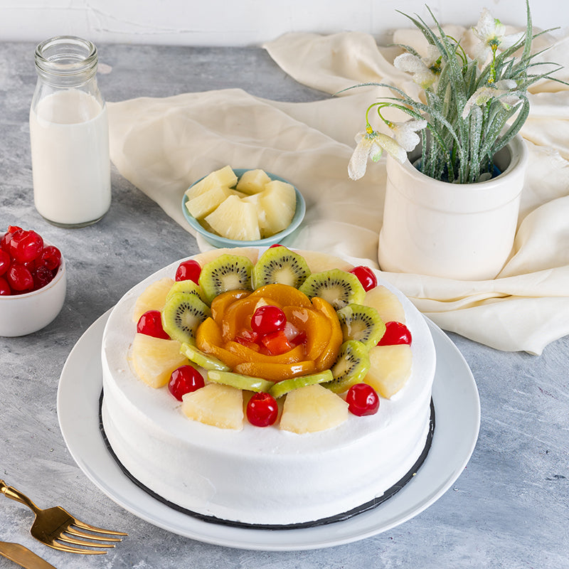 "Kitchen Cuisine Mixed Fruit Cake topped with pineapple, kiwi, cherries, and peaches, available in Lahore, Karachi, and Islamabad"