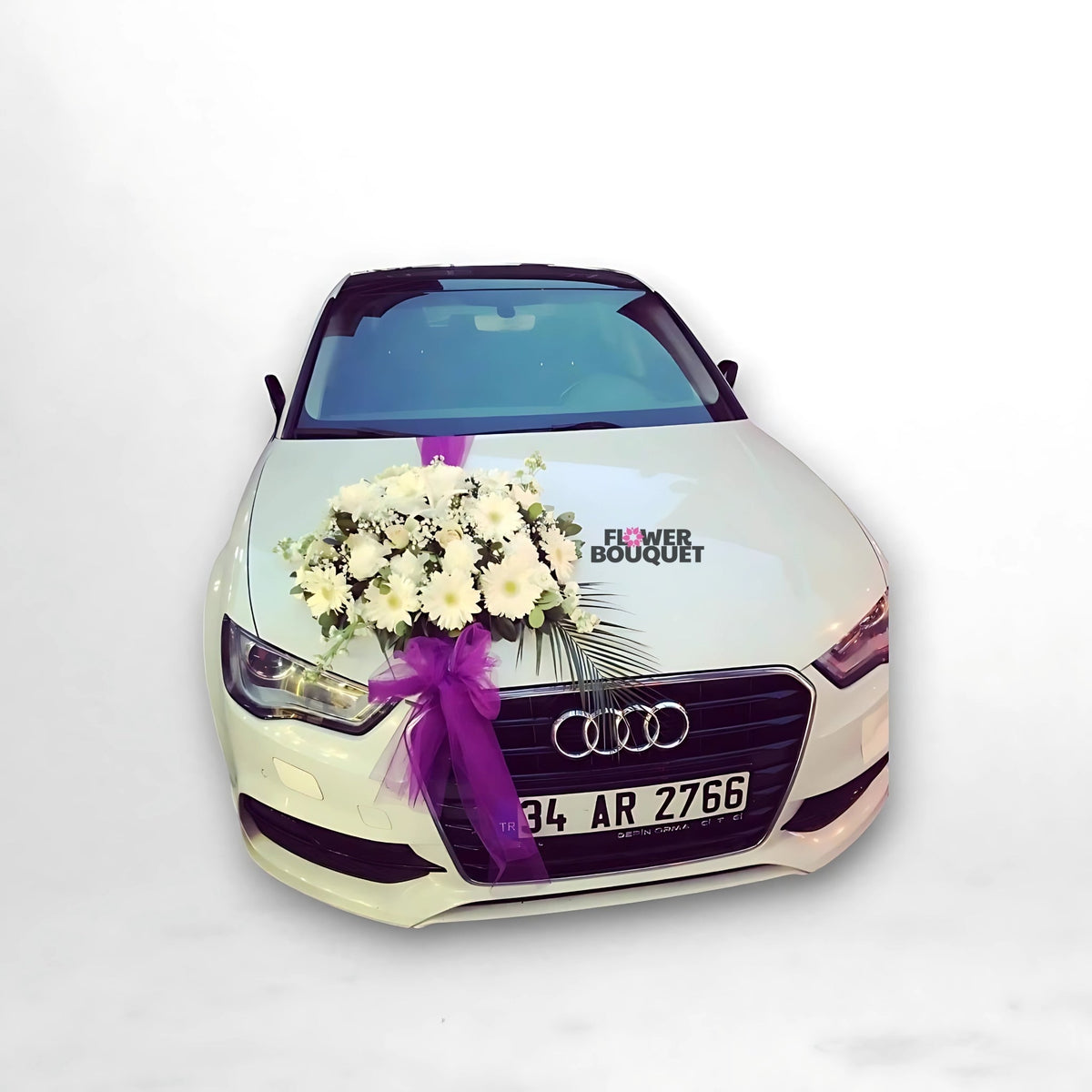 White Audi car decorated with white flowers and greenery on the hood, tied with a purple ribbon.