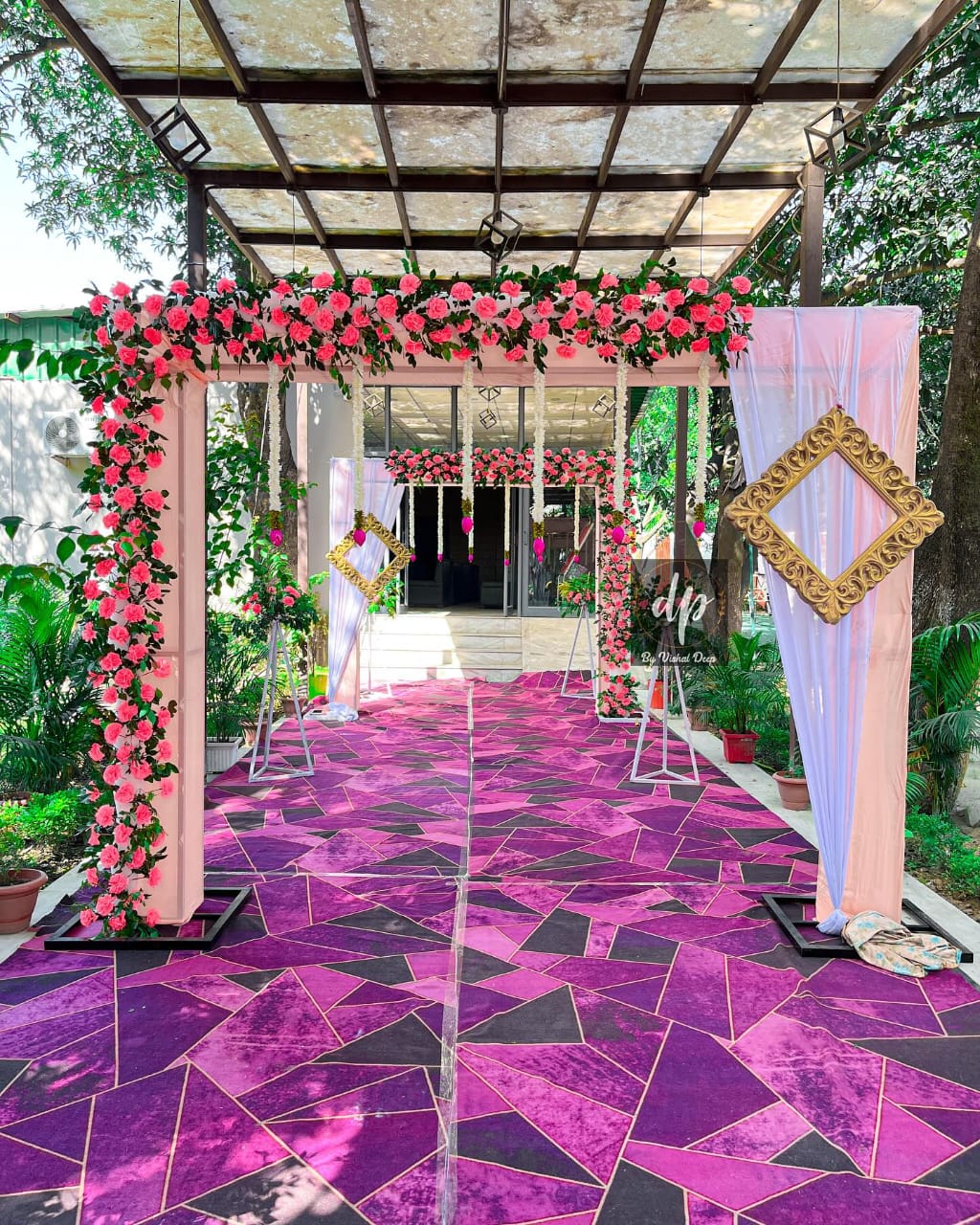 Walkway decor with pink and white floral arches and draped curtains.