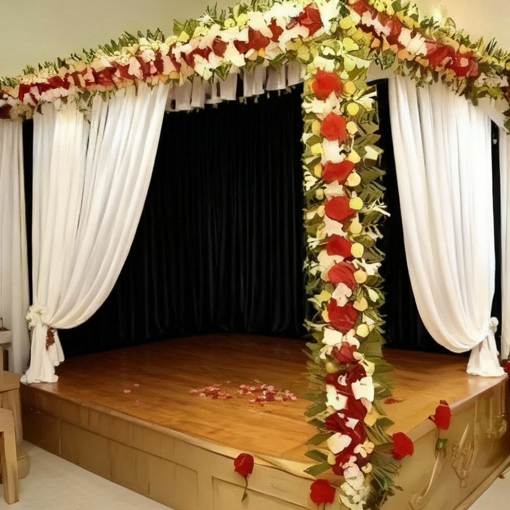 Romantic canopy flower decoration with red and white flowers, green leaves, and white lights creating an enchanting ambiance.