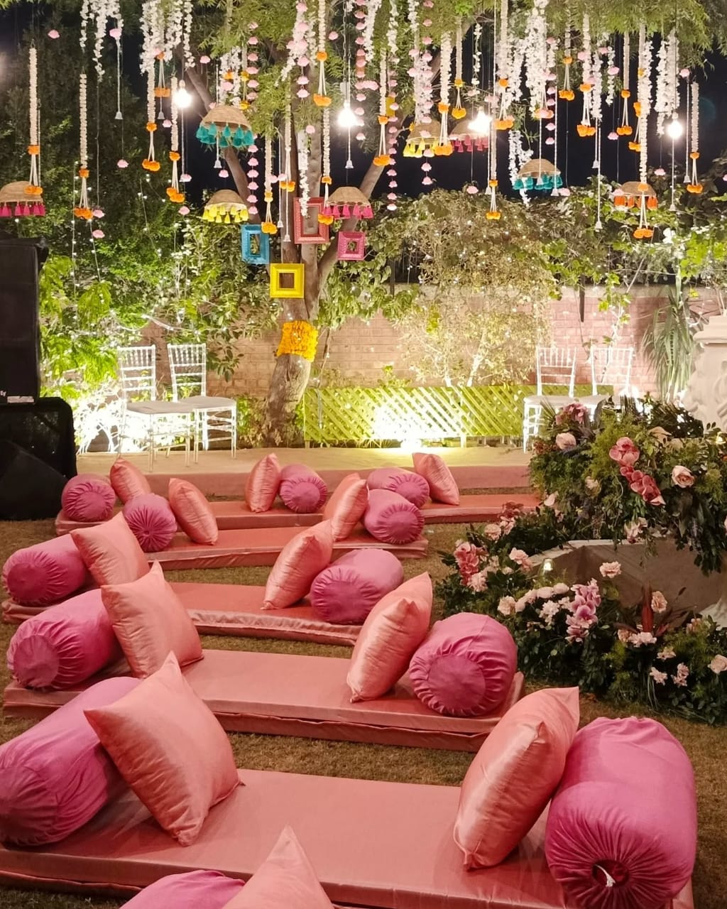 Outdoor seating setup with pink cushions, hanging lanterns, and colorful decor.