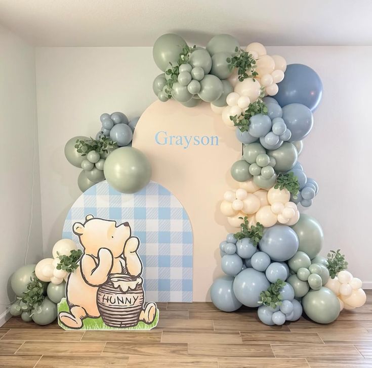 Winnie the Pooh baby shower balloon backdrop with pastel balloons and greenery