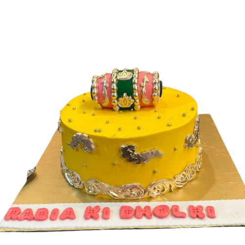 Yellow dholki wedding cake with golden designs, pearls, and colorful dholki topper